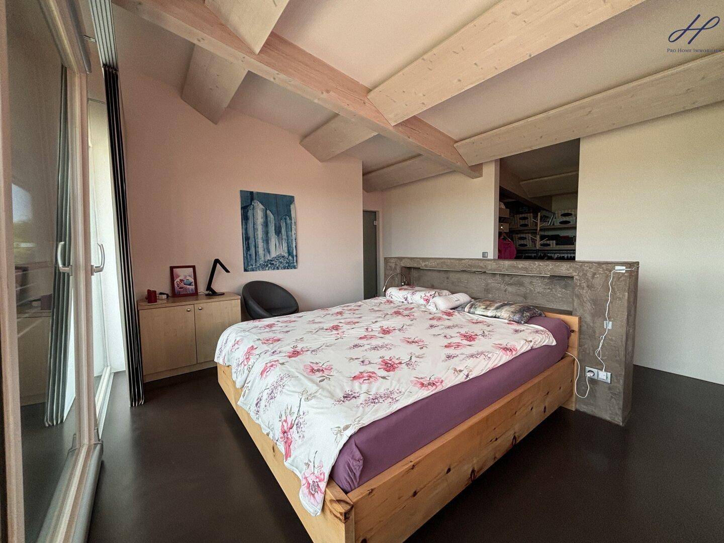 Gemütliches Schlafzimmer mit Holzbett und Blick auf die Landschaft.