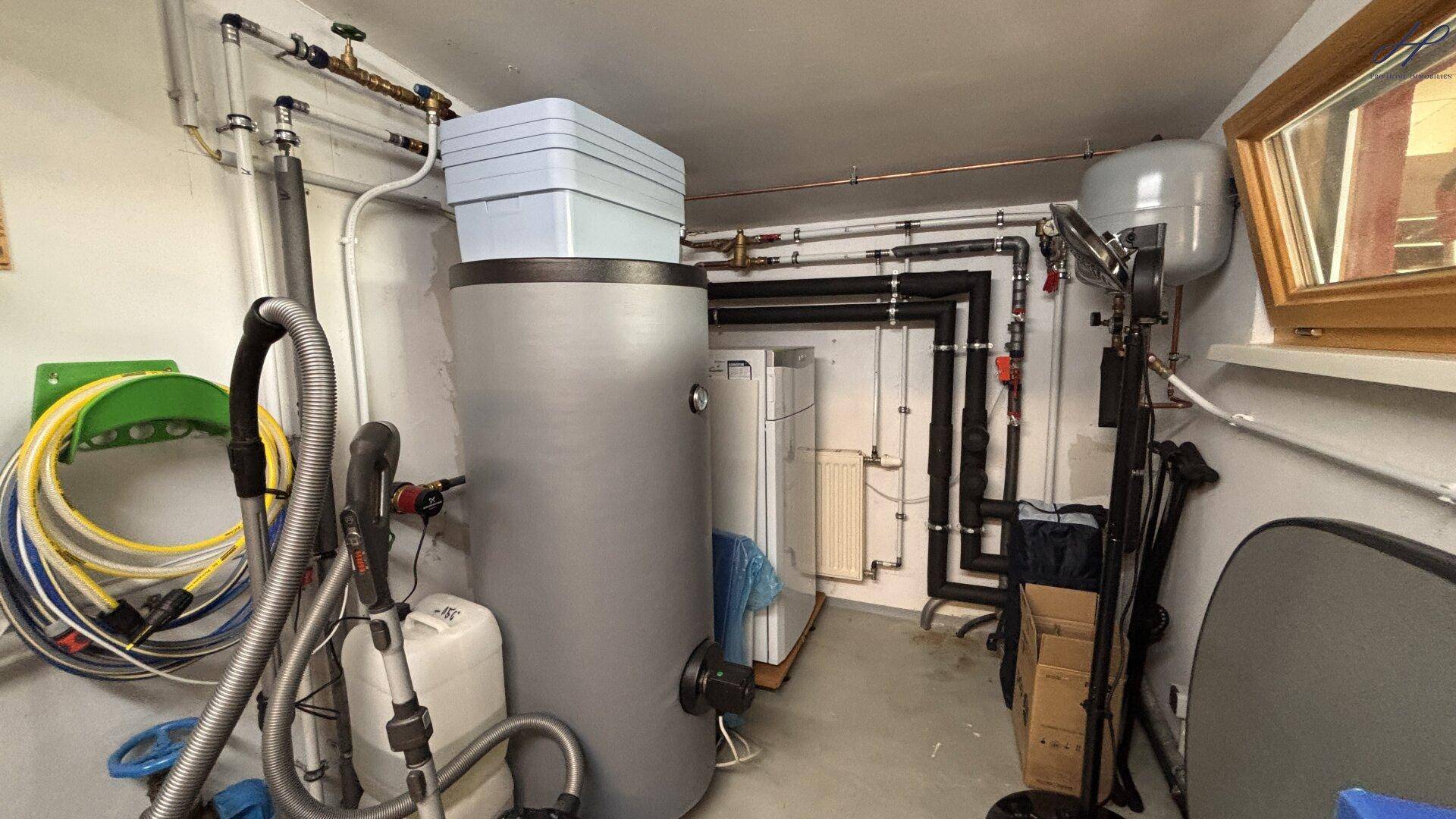 Technikraum mit Heizungsanlage, Warmwasserspeicher und verschiedenen Installationen.