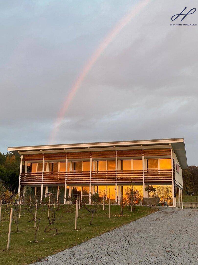 Modernes Haus bei Sonnenuntergang mit Regenbogen am Himmel.