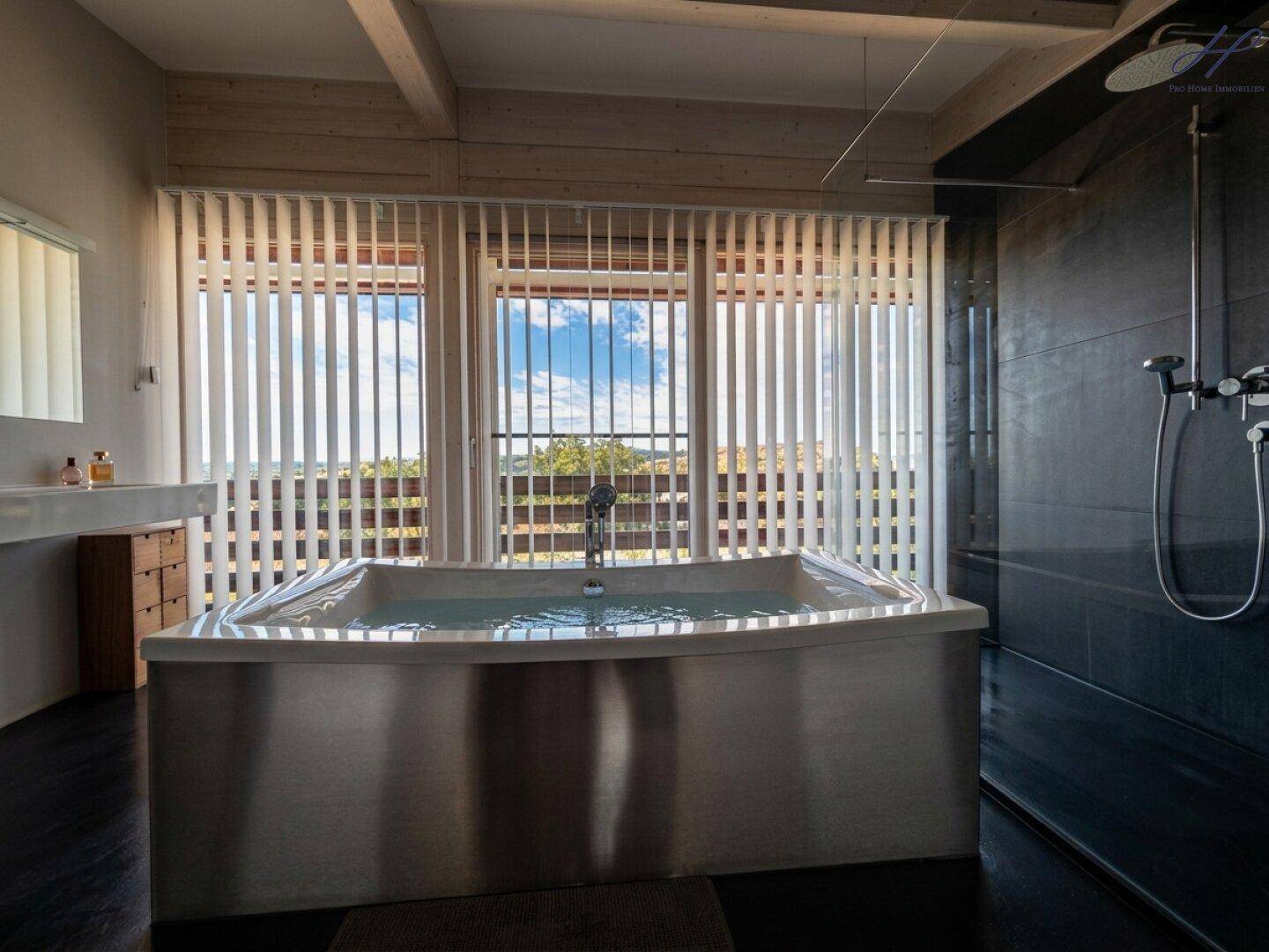 Modernes Badezimmer mit großer Badewanne und Dusche, bietet weite Ausblicke.