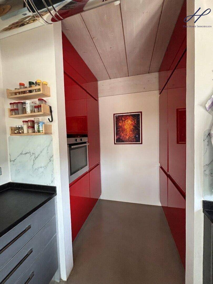 Praktische Speisekammer oder zusätzliche Küchenzeile mit roten Schränken und Backofen.