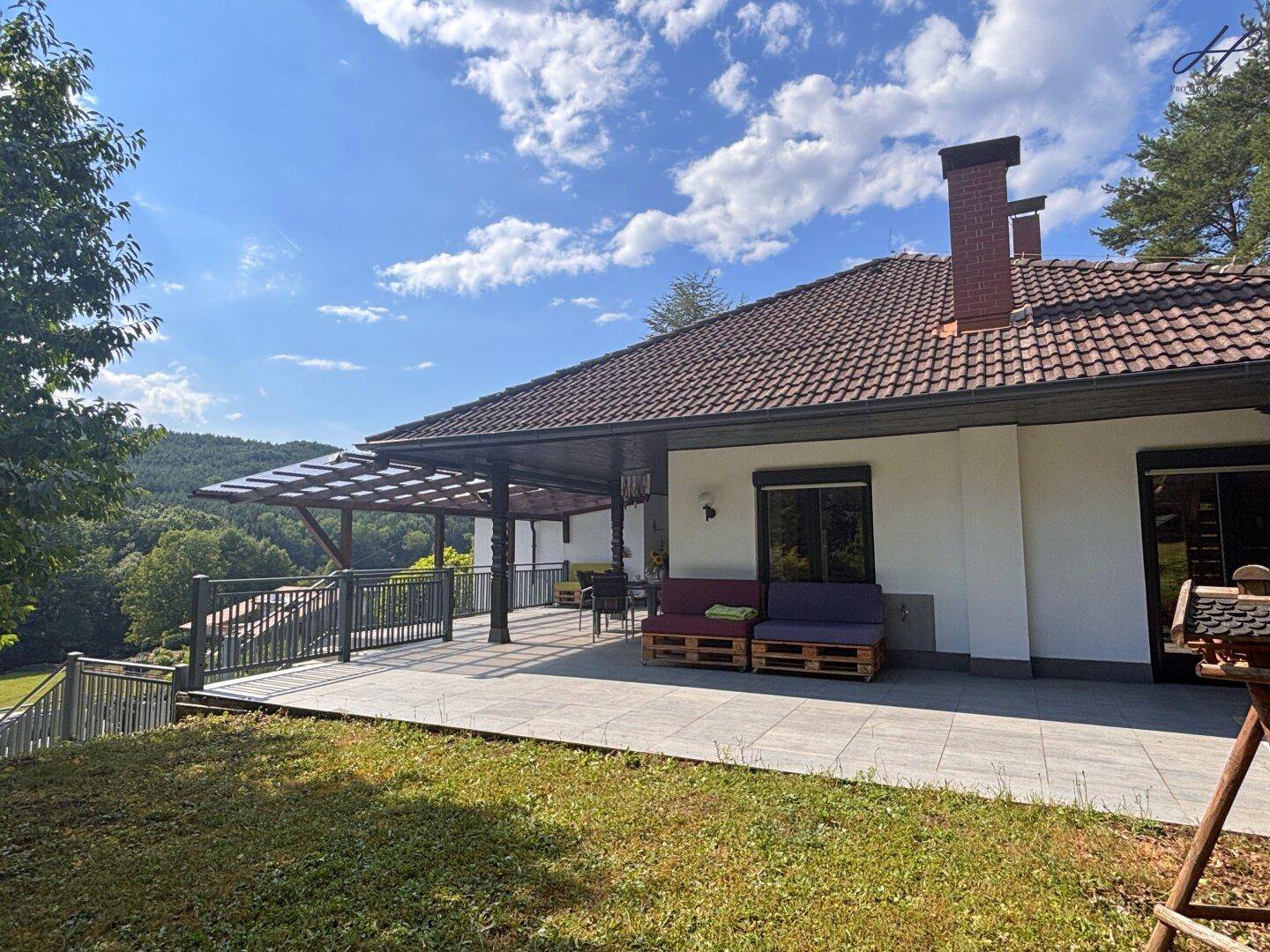 Große überdachte Terrasse mit weitem Blick ins Grüne und auf die Landschaft.