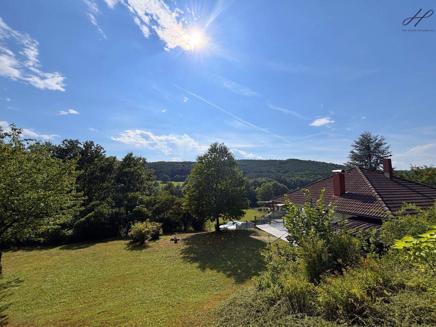 Weitläufiger Gartenbereich mit Panoramablick auf das Haus und die grüne Hügellandschaft.