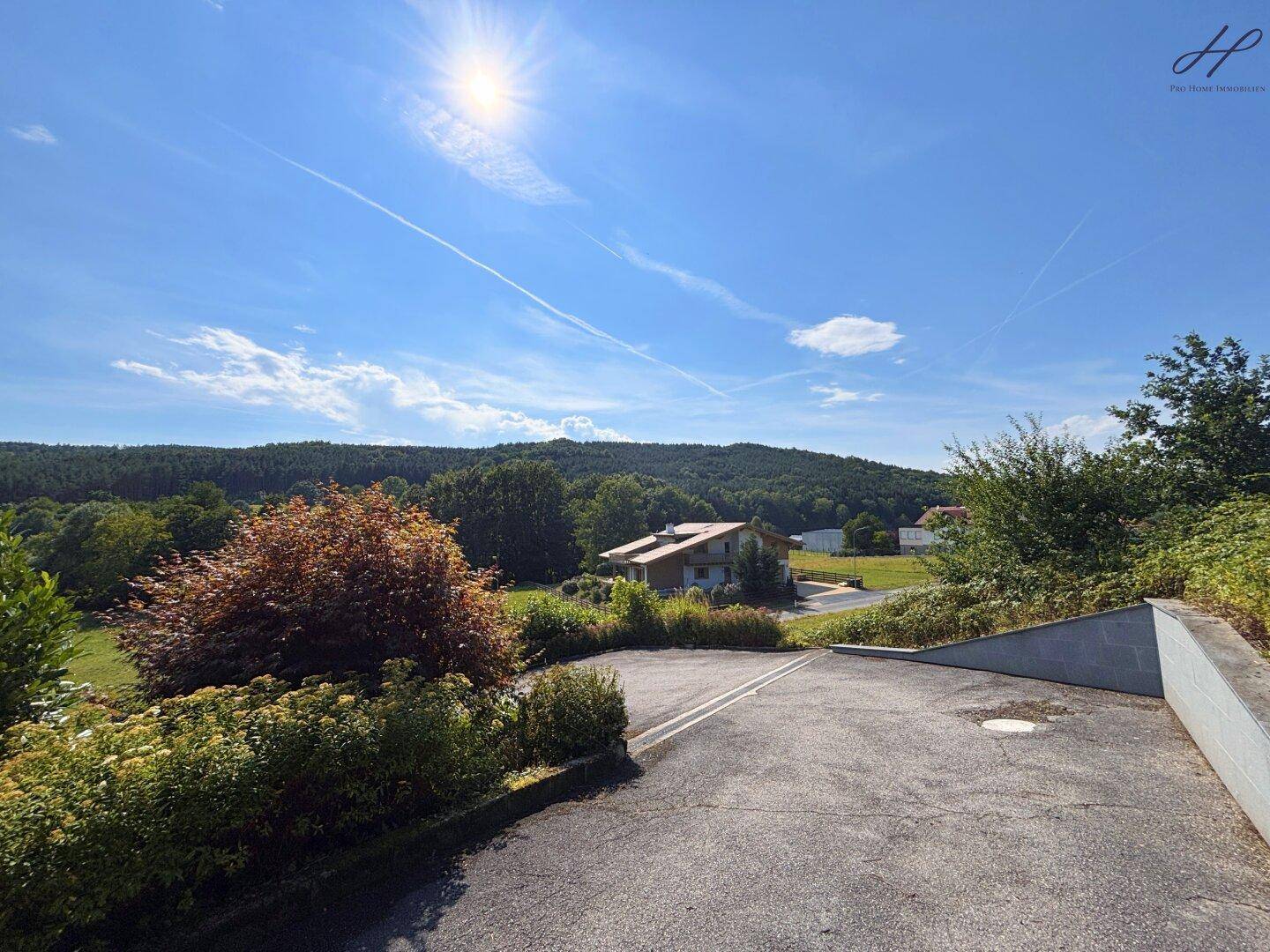 Parkplatz mit weitem Blick über die grüne Landschaft und die umliegenden Häuser.