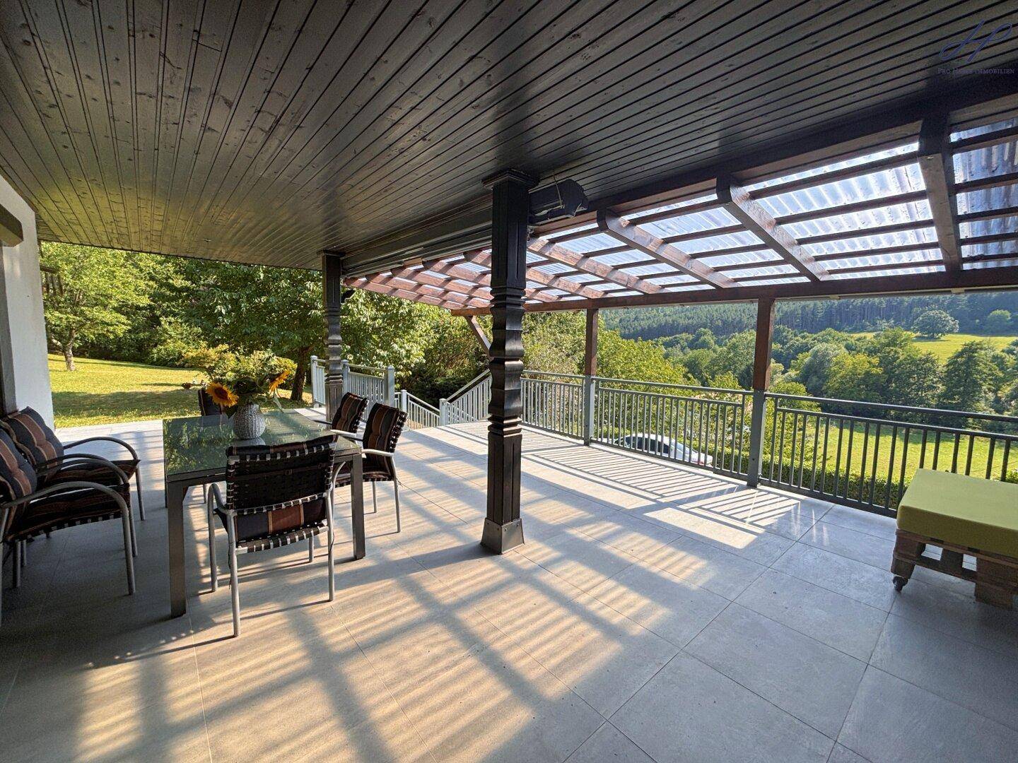 Helle, überdachte Terrasse mit Essbereich und Lounge-Möbeln, ideal für Entspannung im Freien.