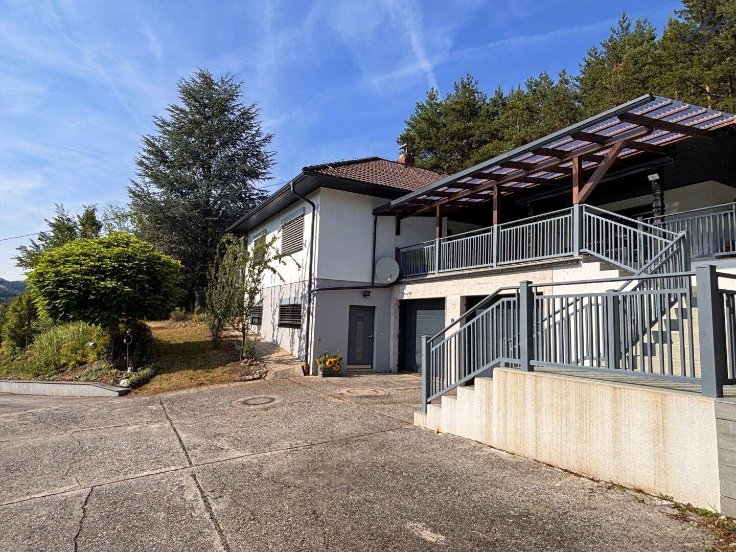 Eingangsbereich des Hauses mit Zufahrt, Treppe zur Terrasse und Garagen.