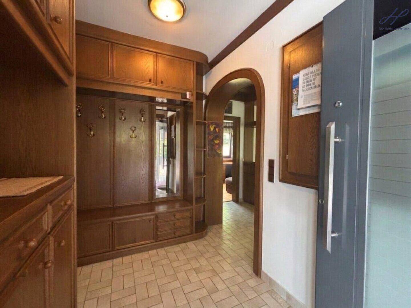 Gemütlicher Eingangsbereich mit Holzgarderobe, Spiegel und gefliestem Boden.