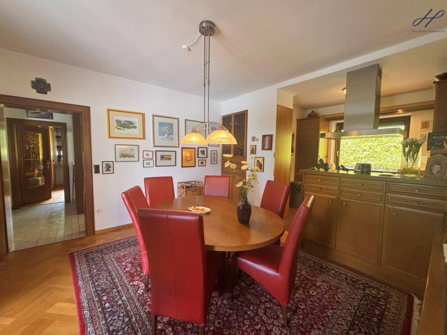 Essbereich mit Parkettboden und Blick in die angrenzende Küche, dekoriert mit Kunstwerken.