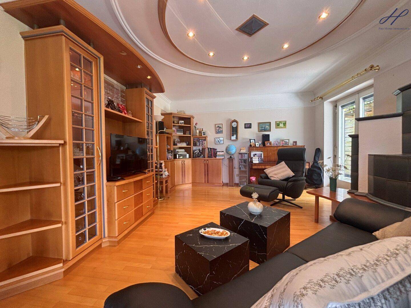 Geräumiges Wohnzimmer mit Parkettboden, dekorativer Decke und Holzmöbeln.