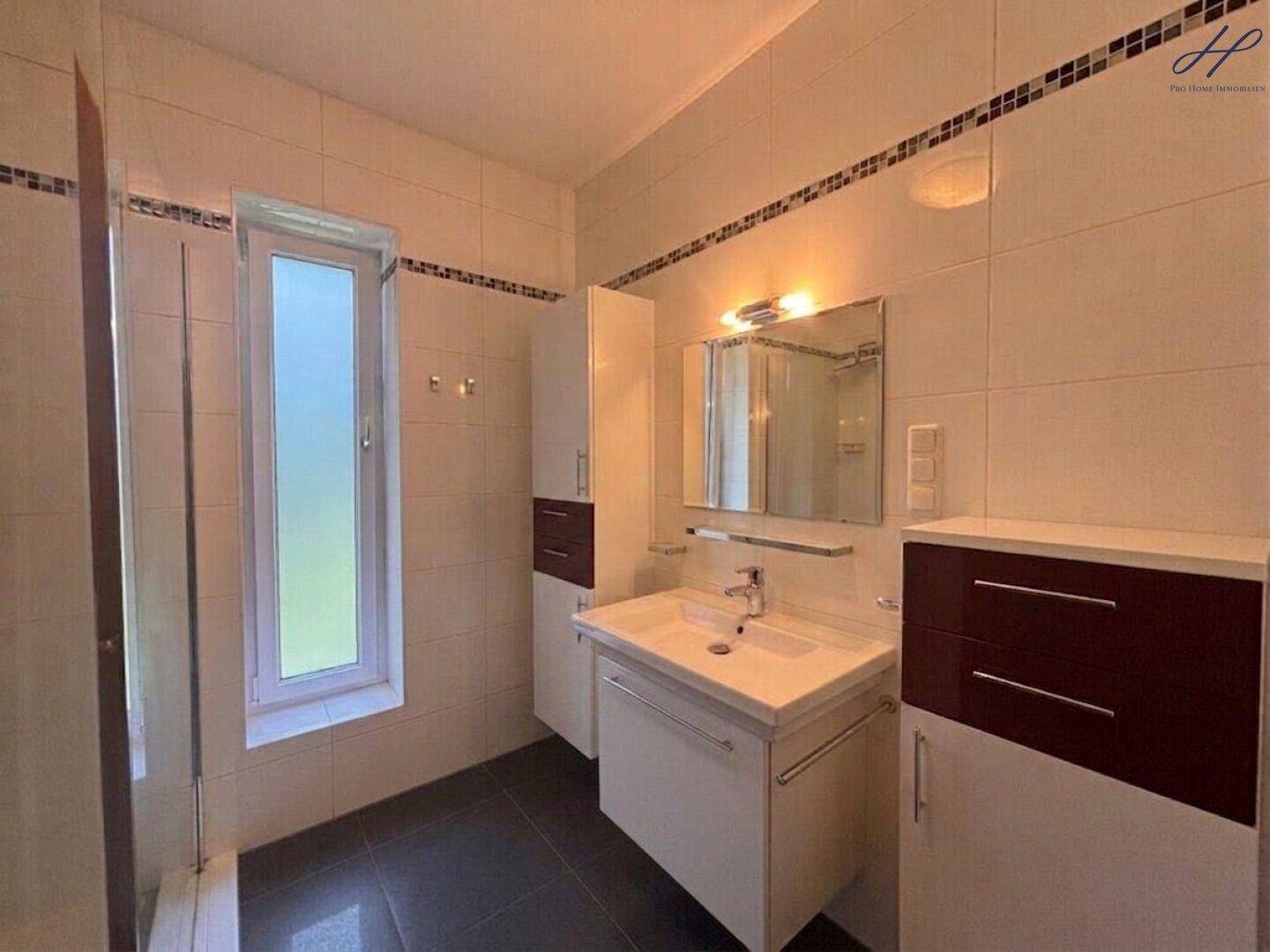 Modernes Badezimmer mit Dusche, Einzelwaschbecken und Fenster.