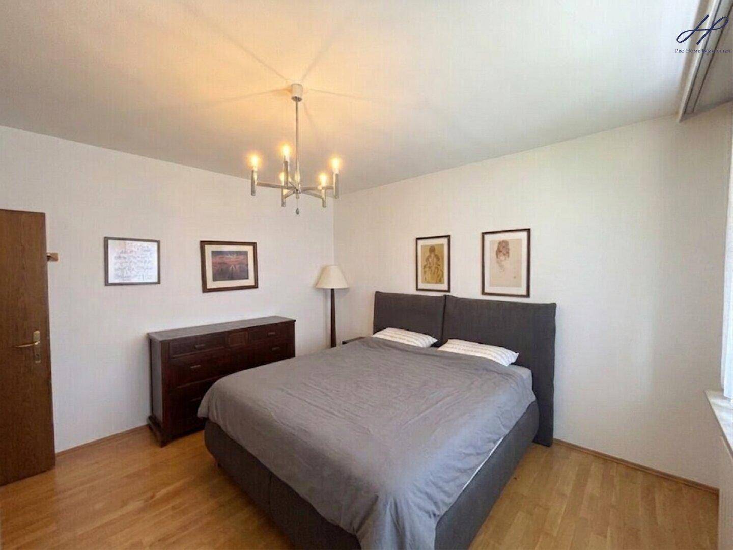 Schlafzimmer mit Holzboden, Doppelbett und schlichter Einrichtung.