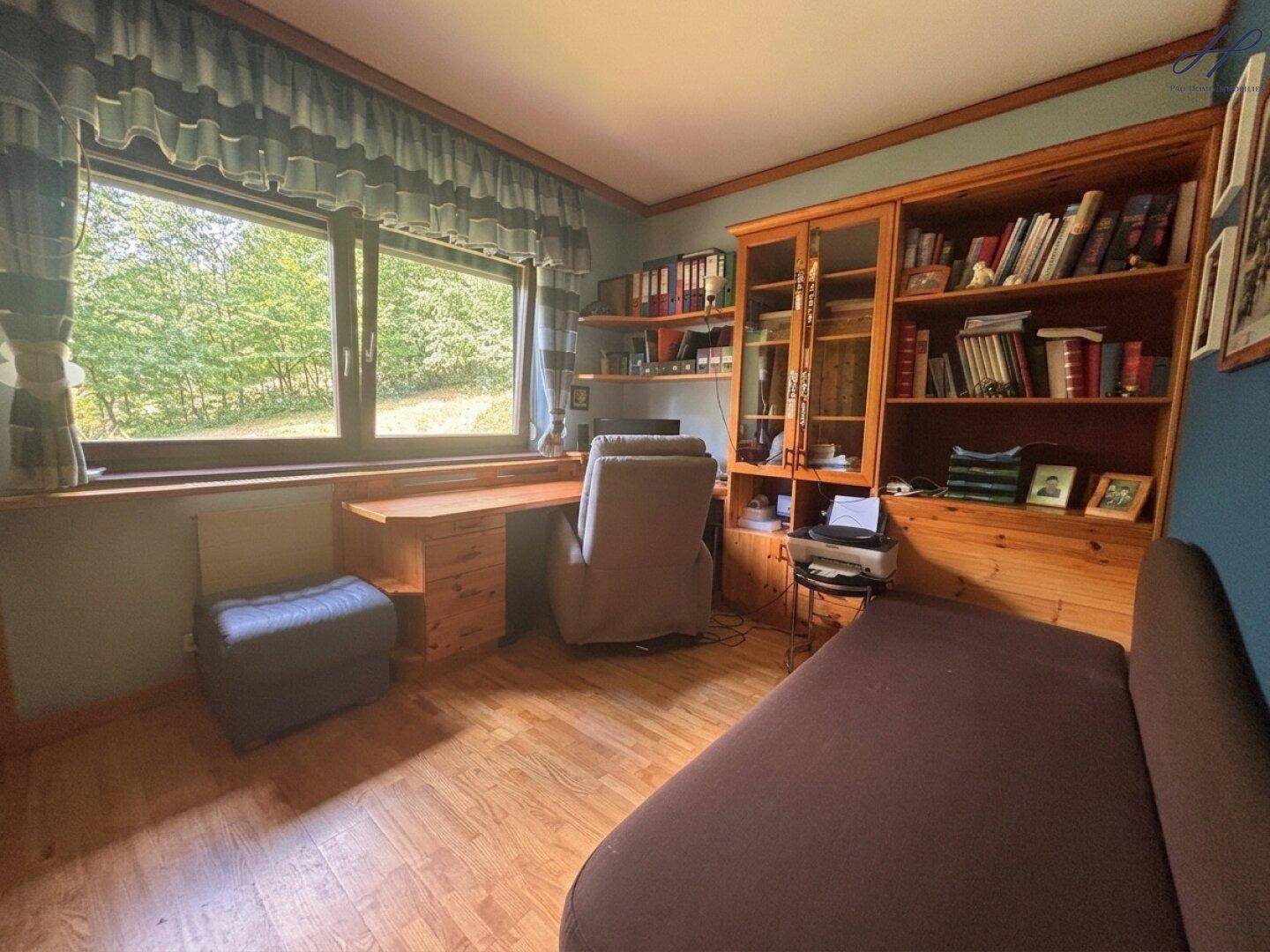 Arbeitszimmer mit großem Fenster, Holzboden und eingebauten Holzregalen.
