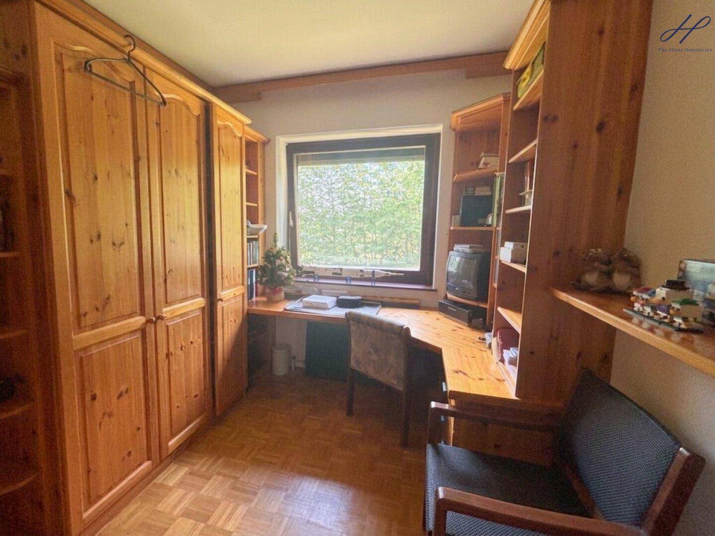 Arbeitszimmer mit Holzboden, Einbauschränken und Blick ins Grüne.