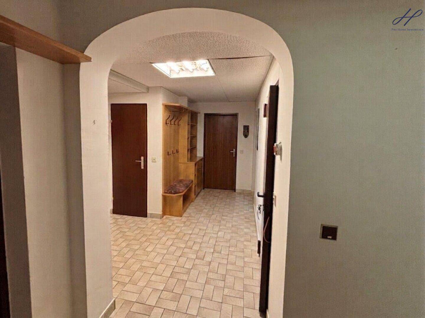 Eingangsbereich mit Fliesenboden, Garderobe und Holztüren.