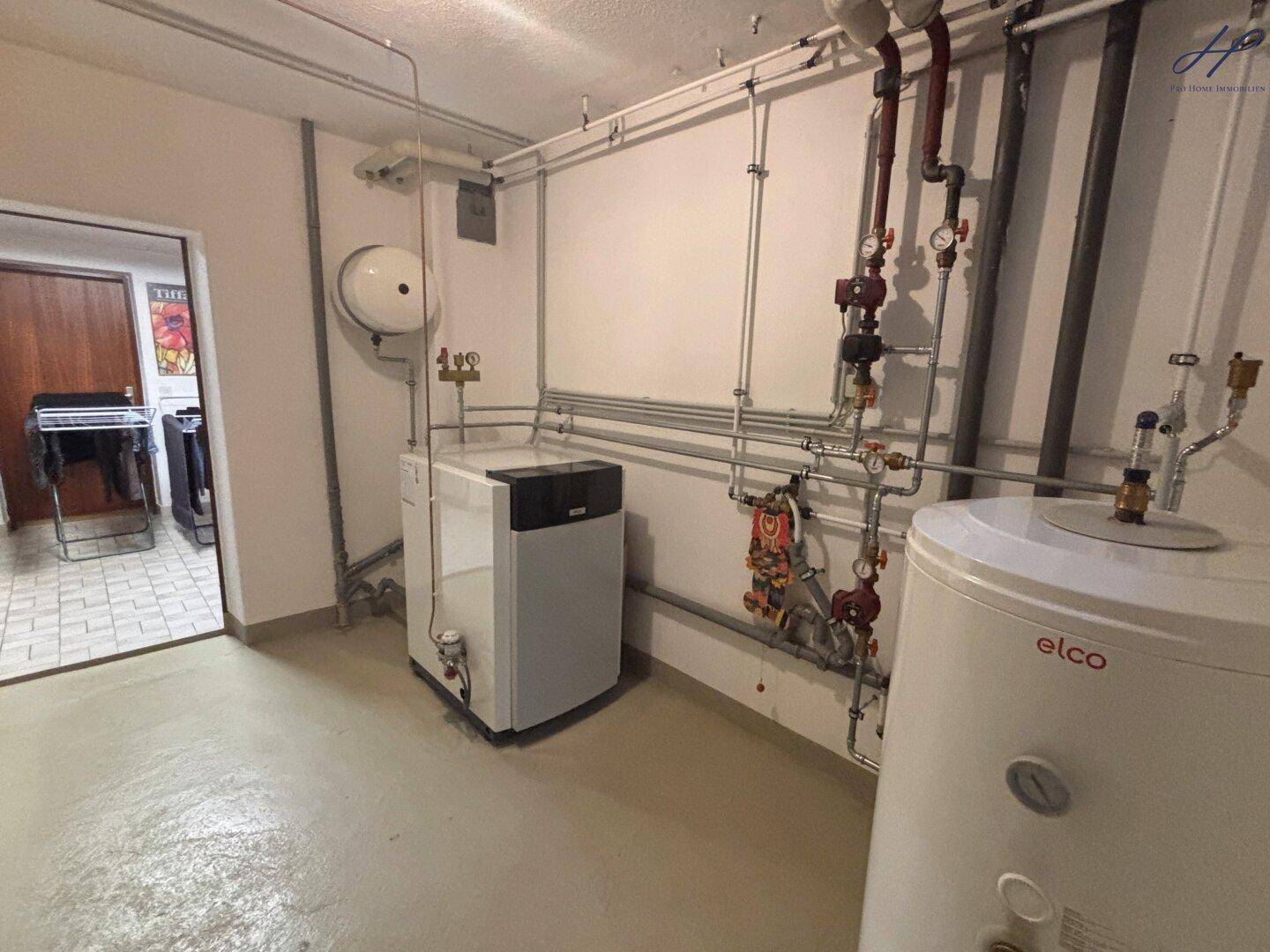 Technikraum mit Heizungsanlage, Warmwasserspeicher und Rohrleitungen.