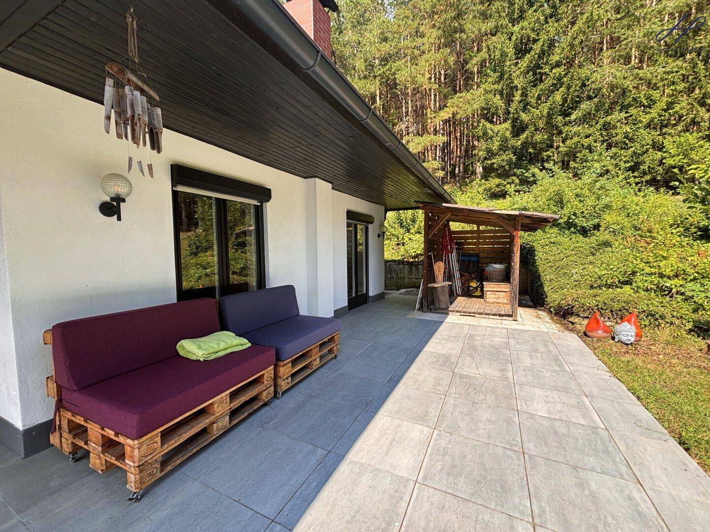 Terrasse mit Palettenmöbeln, Fliesenboden und Zugang zum Garten.