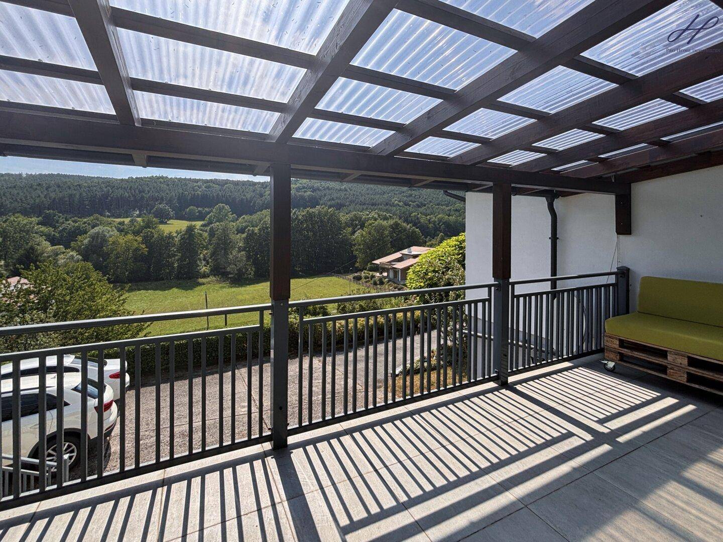 Überdachte Terrasse mit Sitzgelegenheiten und weitem Blick ins Grüne, ideal zum Entspannen.