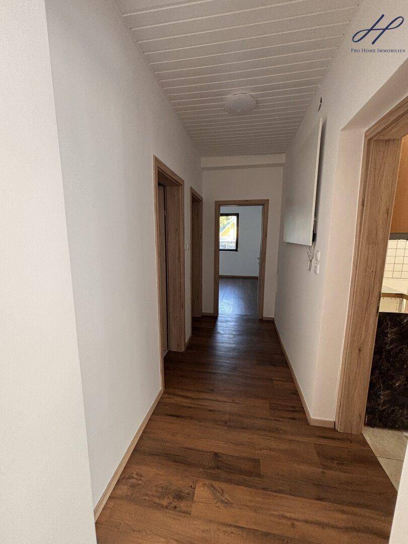 Heller Flur mit Laminatboden und Holztüren, der zu weiteren Räumen führt.