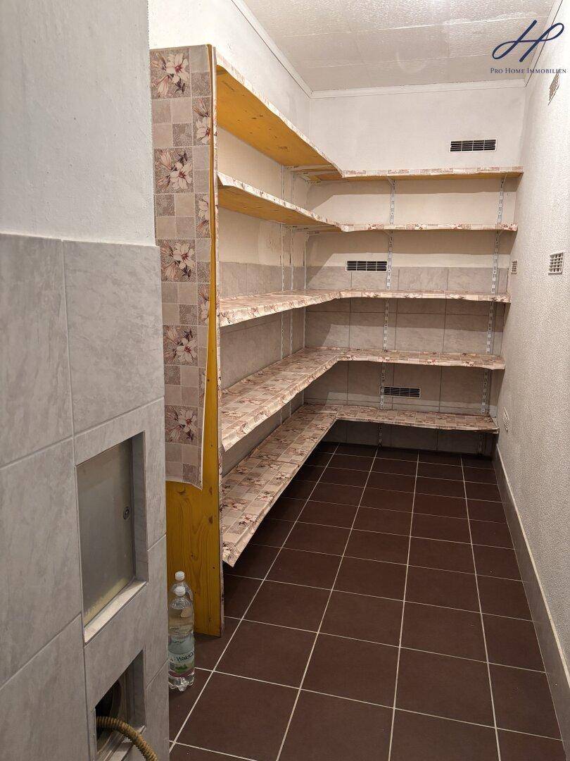 Praktische Speisekammer mit vielen Regalen und Fliesenboden für Vorräte.