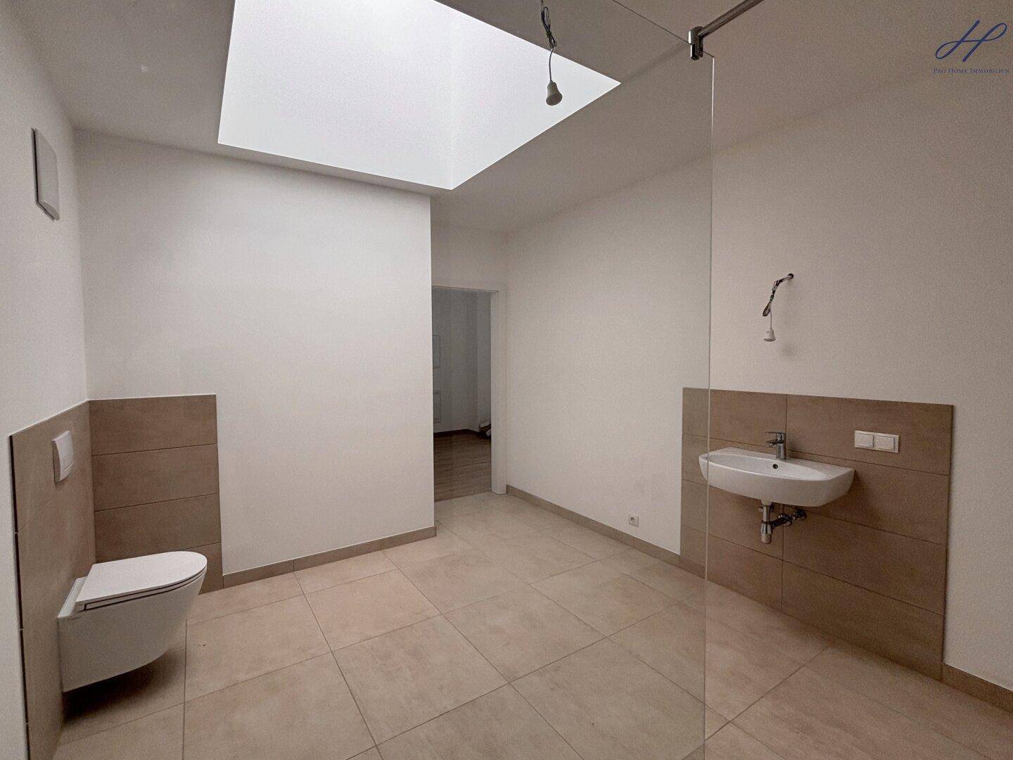 Helles Badezimmer mit modernem Waschtisch, Wand-WC und Oberlicht für angenehmes Tageslicht.