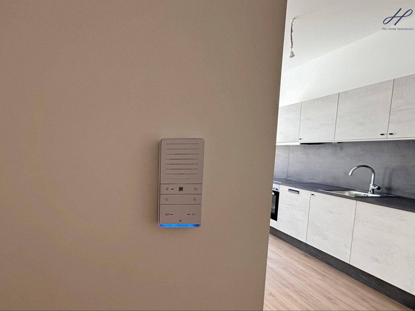 Modernes Gegensprechanlagensystem an der Wand mit Blick auf die angrenzende Küchenzeile.