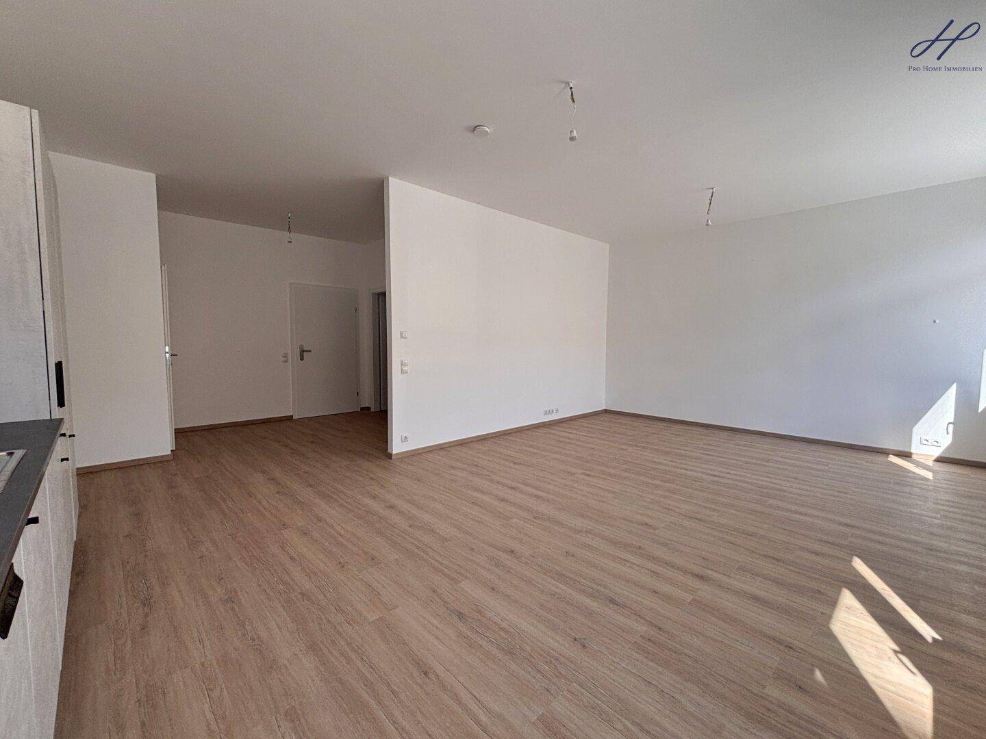 Geräumiger, heller Wohnbereich mit modernem Vinylboden und weißen Wänden, bereit zur Einrichtung.