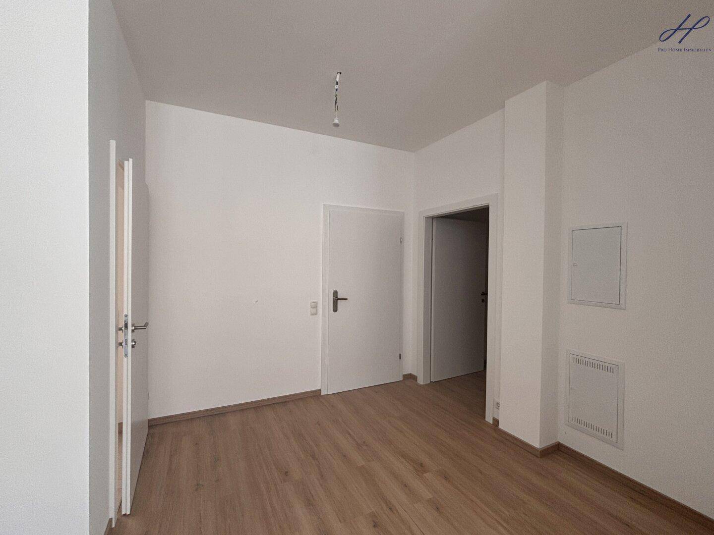 Heller Flur mit Vinylboden und weißen Wänden, der zu weiteren Räumen führt.