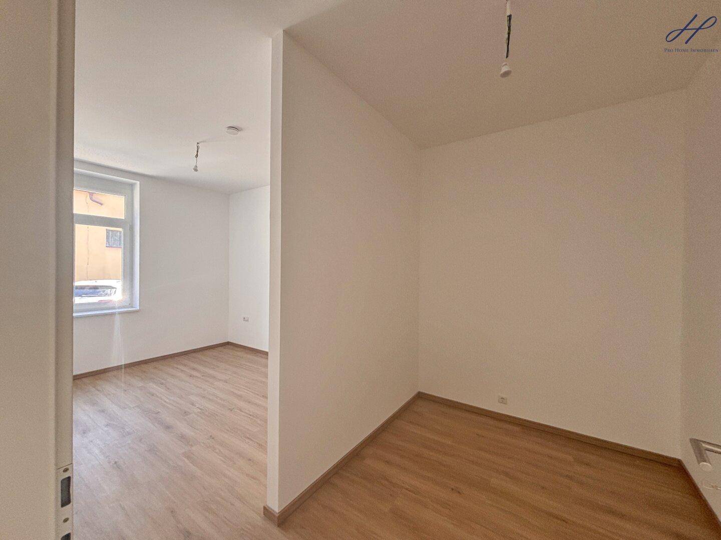 Kleiner, heller Raum mit Vinylboden und Fenster, ideal als Schlaf- oder Arbeitszimmer.