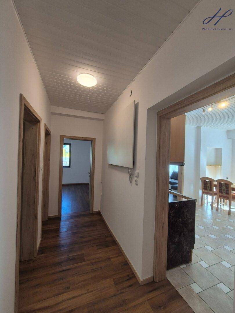 Heller Flur mit Laminatboden und Holztüren, der zu weiteren Räumen führt.