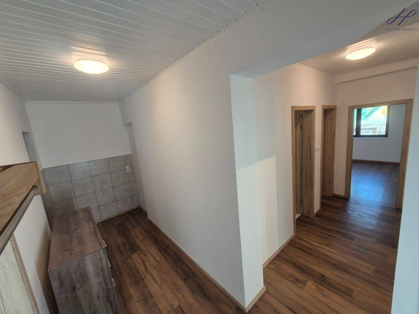 Geräumiger Flurbereich mit Laminatboden und hellem Anstrich, der verschiedene Zimmer verbindet.