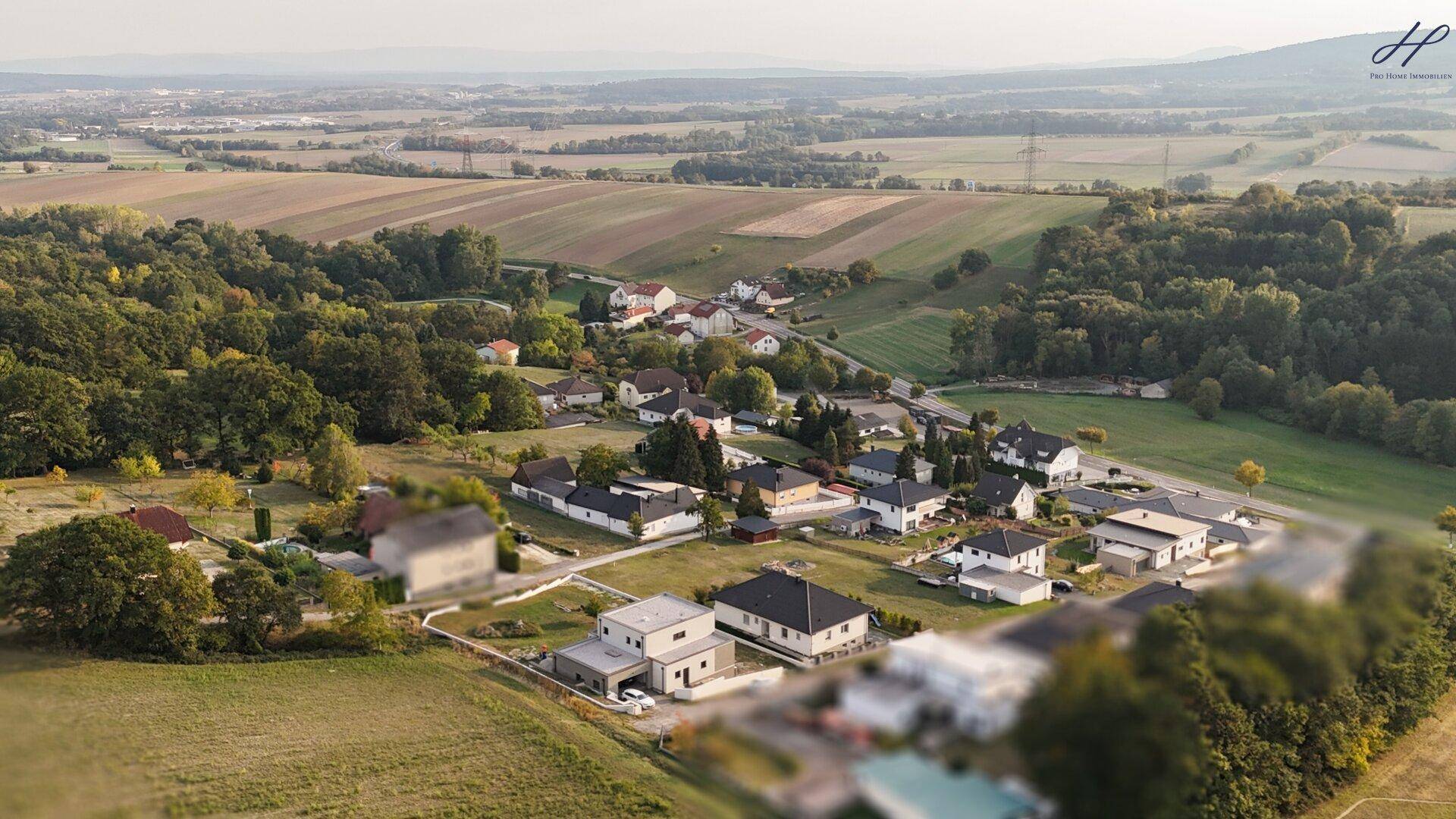 Panoramablick aus der Luft auf das Anwesen und die umliegende idyllische Landschaft mit Dorf.