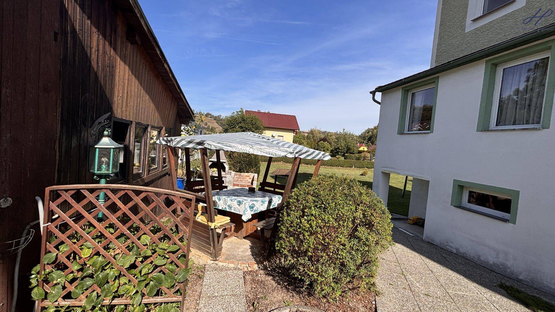 Gemütlicher Sitzbereich im Freien mit Überdachung, ideal für entspannte Stunden im Garten.