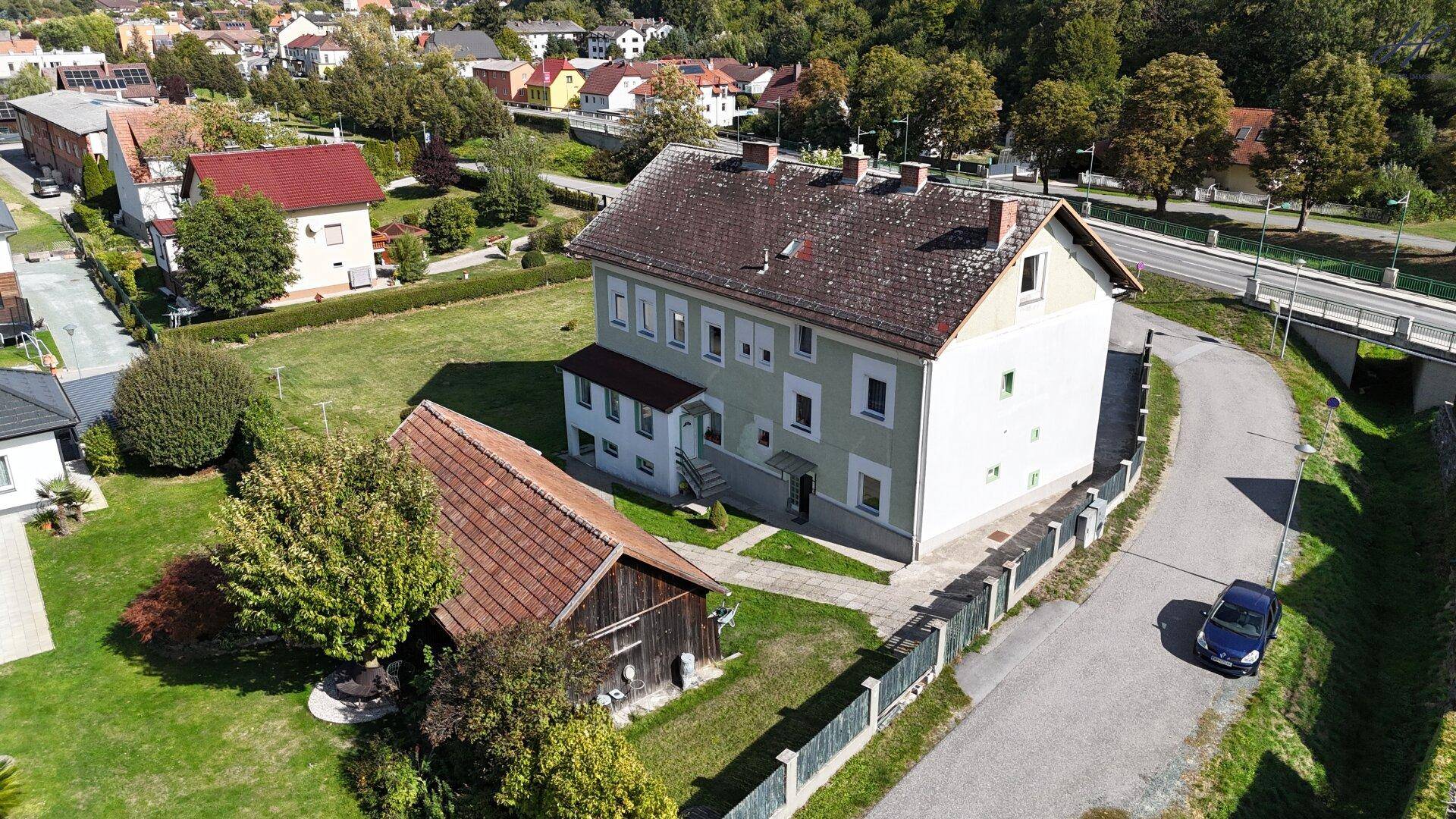Luftaufnahme des Hauses und der Scheune, mit der Straße und der grünen Umgebung.