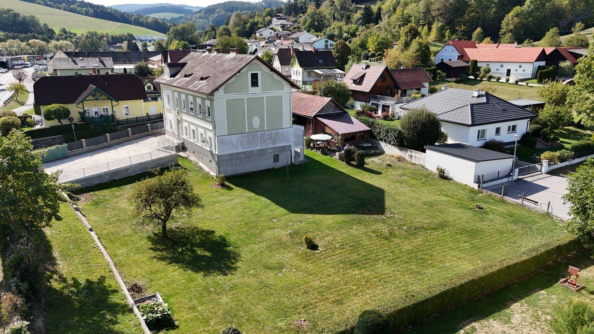 Weitläufiges Grundstück mit einem historischen Gebäude und Blick auf die umliegende Hügellandschaft.