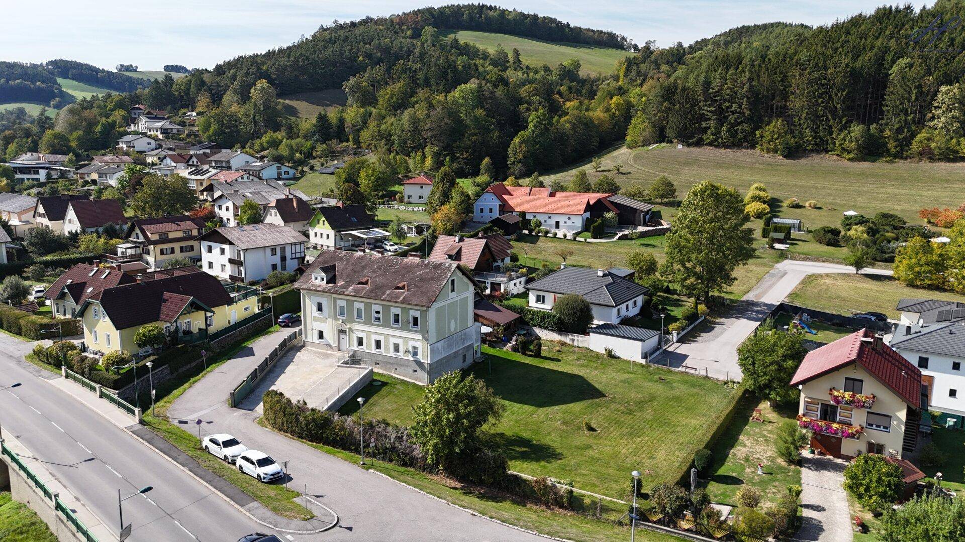 Panoramablick auf ein großes Anwesen mit historischem Gebäude und angrenzender Straße in ländlicher Umgebung.