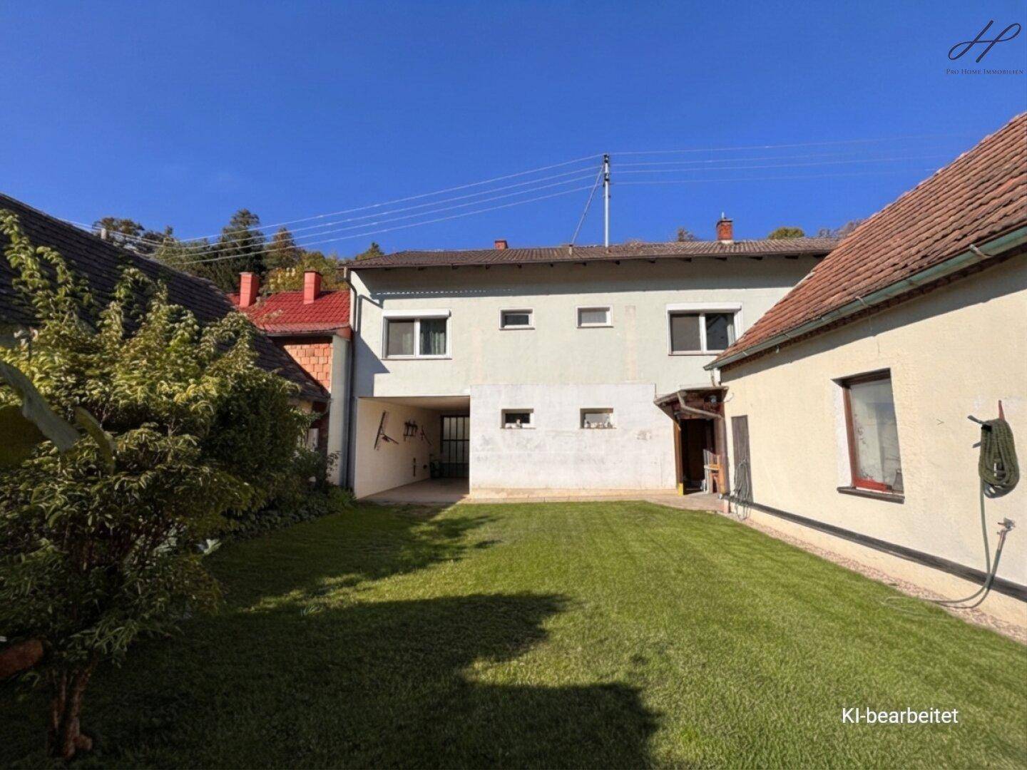 Hinterhof mit Rasenfläche und überdachtem Bereich vor dem Haus.
