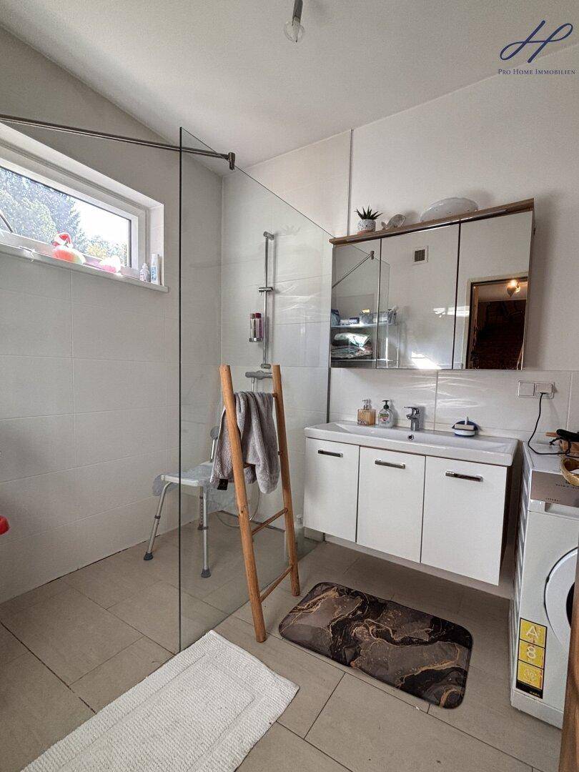 Modernes Badezimmer mit ebenerdiger Dusche, Waschbecken und Fenster.