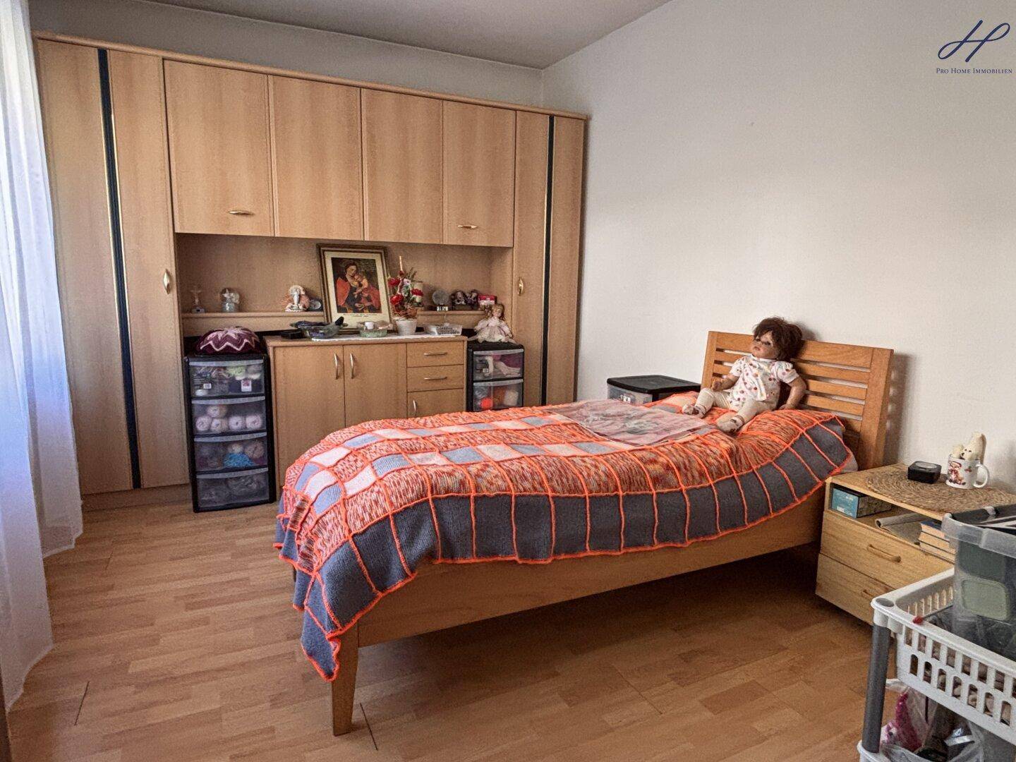 Schlafzimmer mit Holzbett, Einbauschränken und Laminatboden.