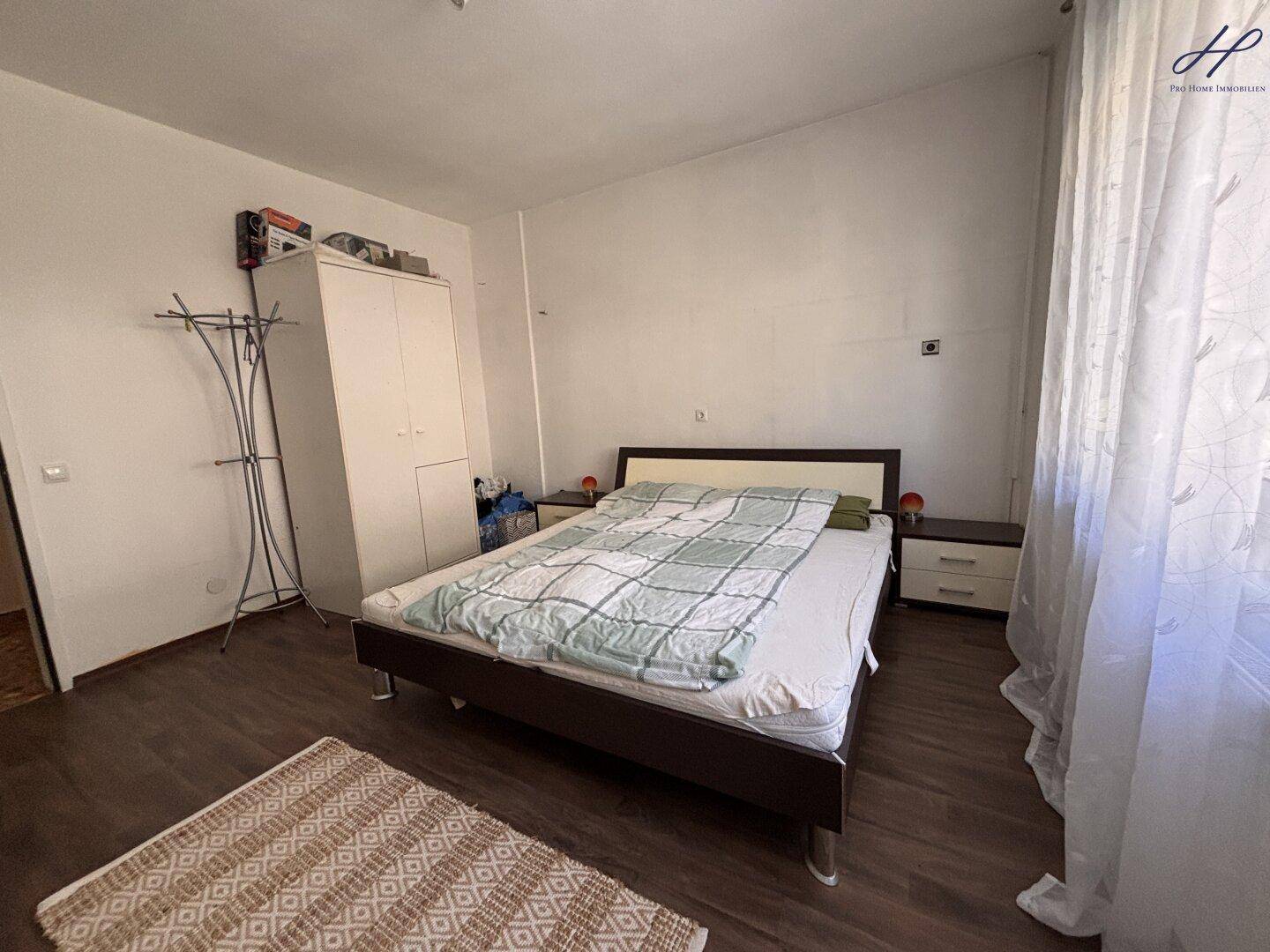 Schlafzimmer mit Doppelbett, Kleiderschrank und Laminatboden.