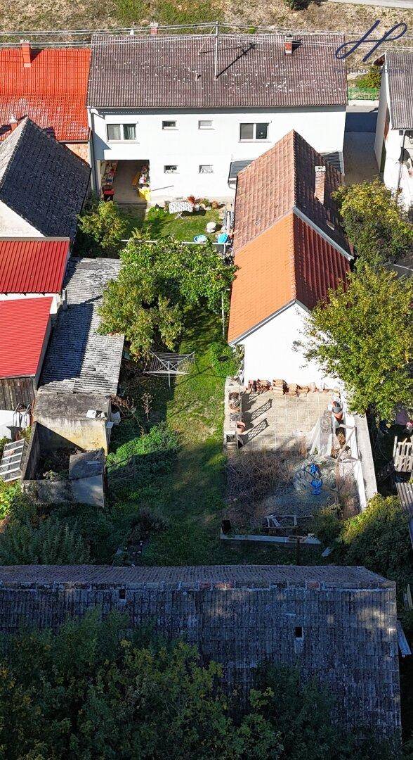 Luftaufnahme mehrerer Wohnhäuser mit Gärten und Dächern in ländlicher Umgebung.