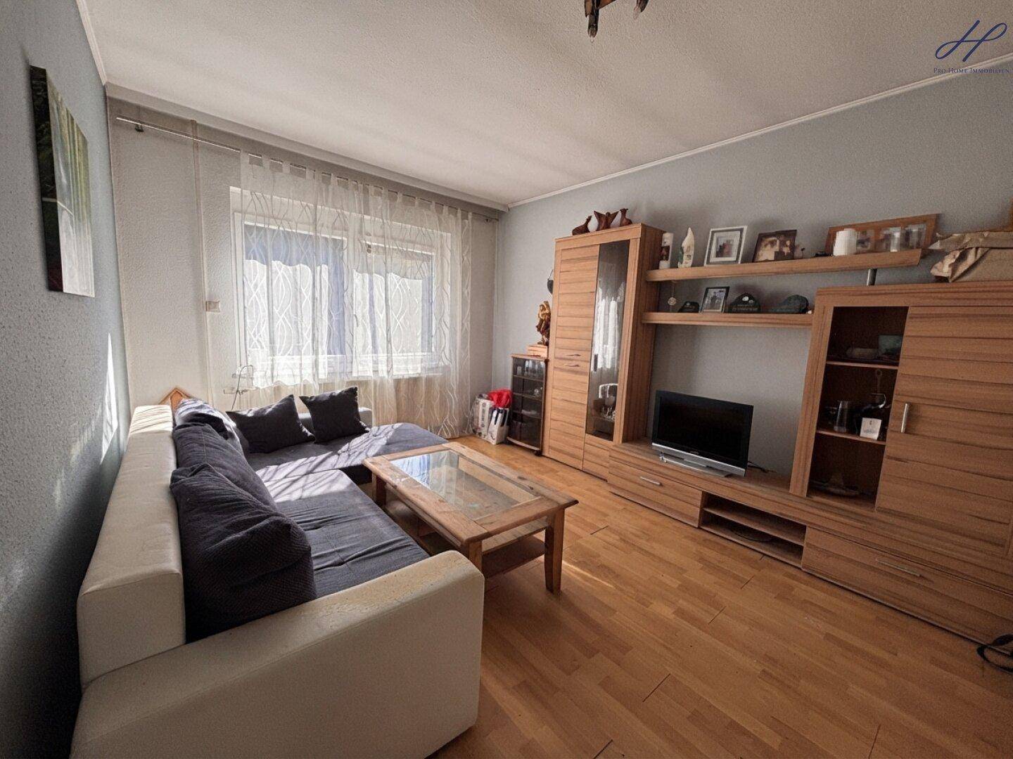 Helles Wohnzimmer mit Sofa, Holzmöbeln und Laminatboden.