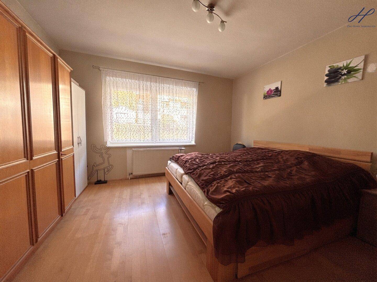 Geräumiges Schlafzimmer mit Doppelbett, Holzschränken und Parkettboden.