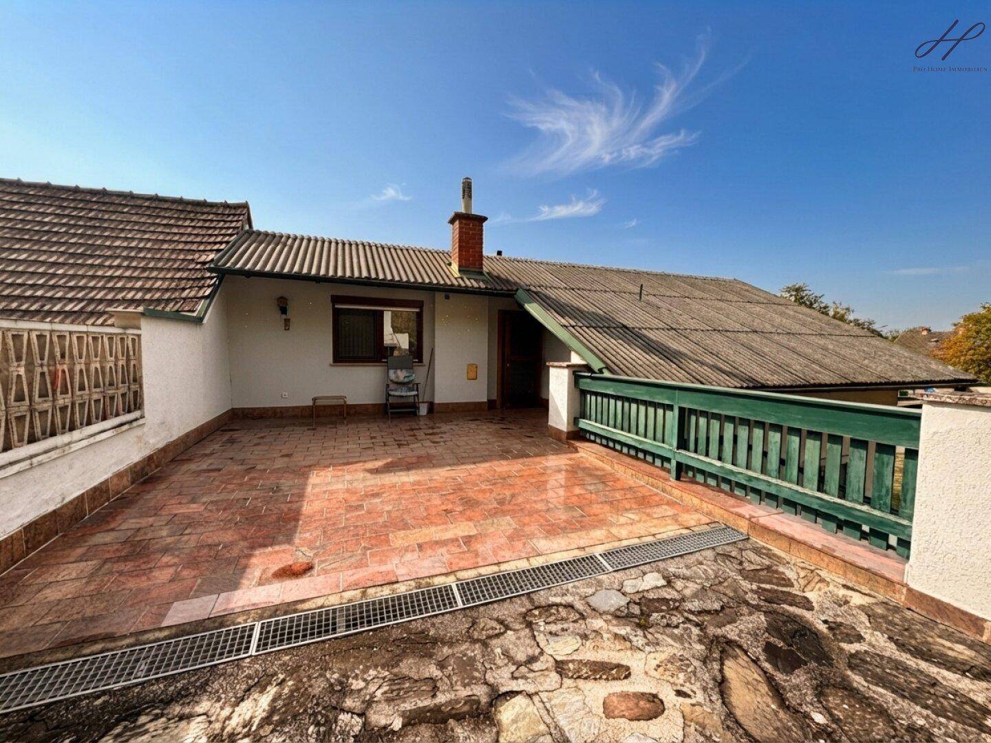 Geräumige Dachterrasse mit Fliesenboden, grüner Brüstung und weitem Blick in die Umgebung.