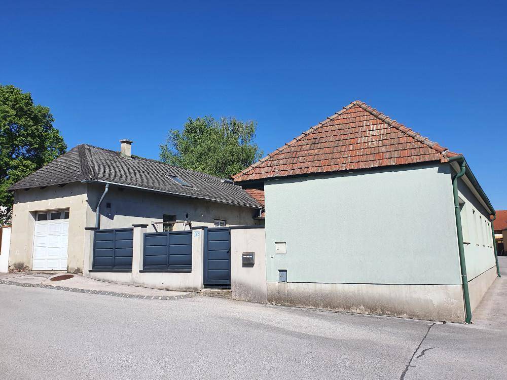 Gesamtansicht des Wohnhauses und der Garage von der Straße unter klarem blauem Himmel.