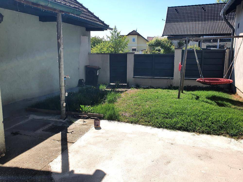 Gepflegter Gartenbereich mit Rasenfläche, Schaukel und Zaun im hinteren Teil des Grundstücks.