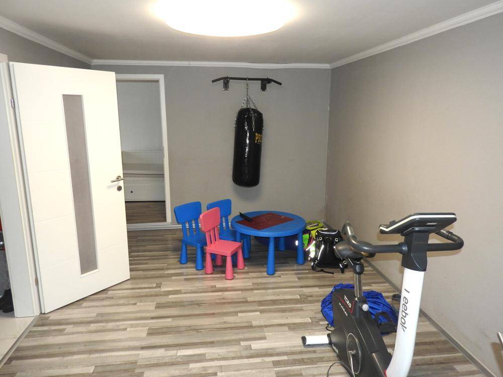 Raum mit Fitnessgerät, Boxsack und Kindermöbeln, genutzt als Sport- und Spielzimmer.