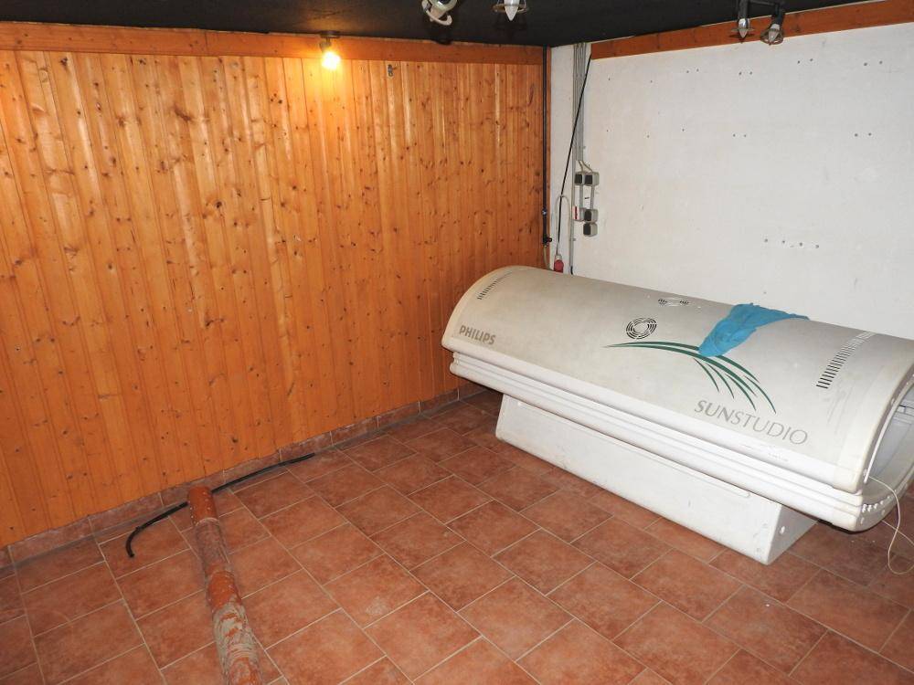 Raum mit Holzverkleidung und einem Solarium, das als Wellnessbereich genutzt werden könnte.
