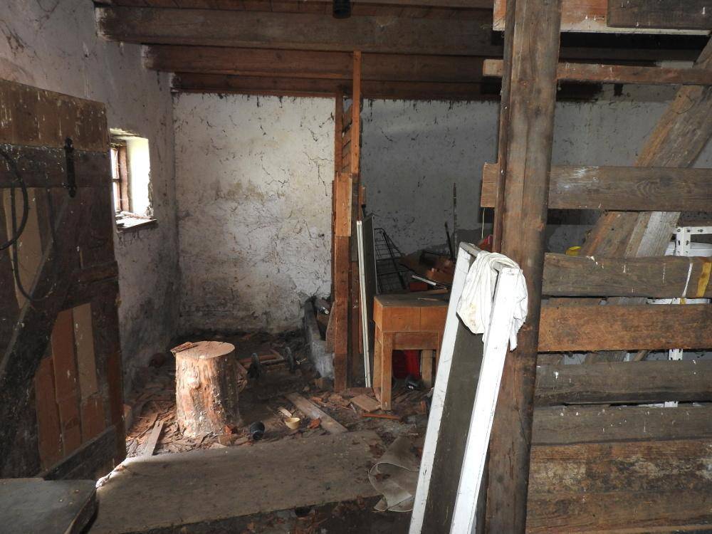 Rustikaler Scheunenraum mit Holzbalken und unfertigen Wänden, als Lagerfläche genutzt.