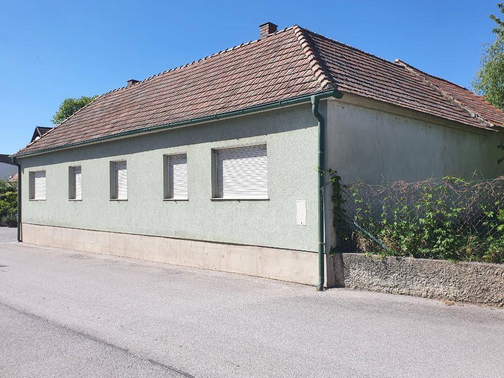 Seitenansicht des Hauses mit mehreren Fenstern, Rollläden und einem gepflegten Ziegeldach.