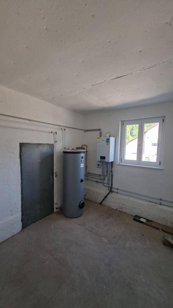 Hauswirtschaftsraum mit Warmwasserspeicher, Heizungsanlage und Fenster.